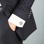 Close-up of a black suit with silver sterling wheel cufflinks and a grey background