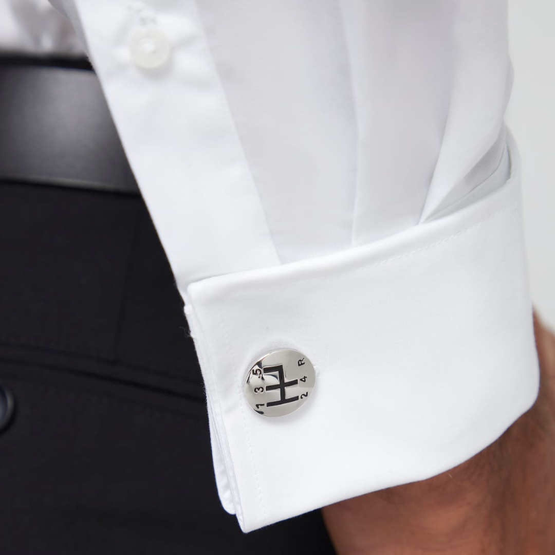 Close-up of a white shirt cuff with a silver gear box cufflink