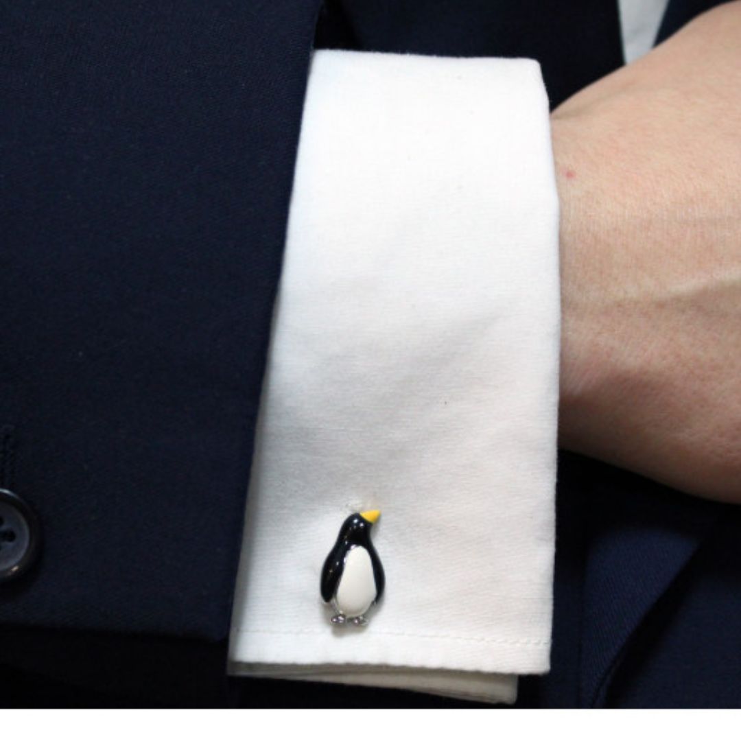 Cufflink shaped like a penguin on a white cuff against a dark suit background