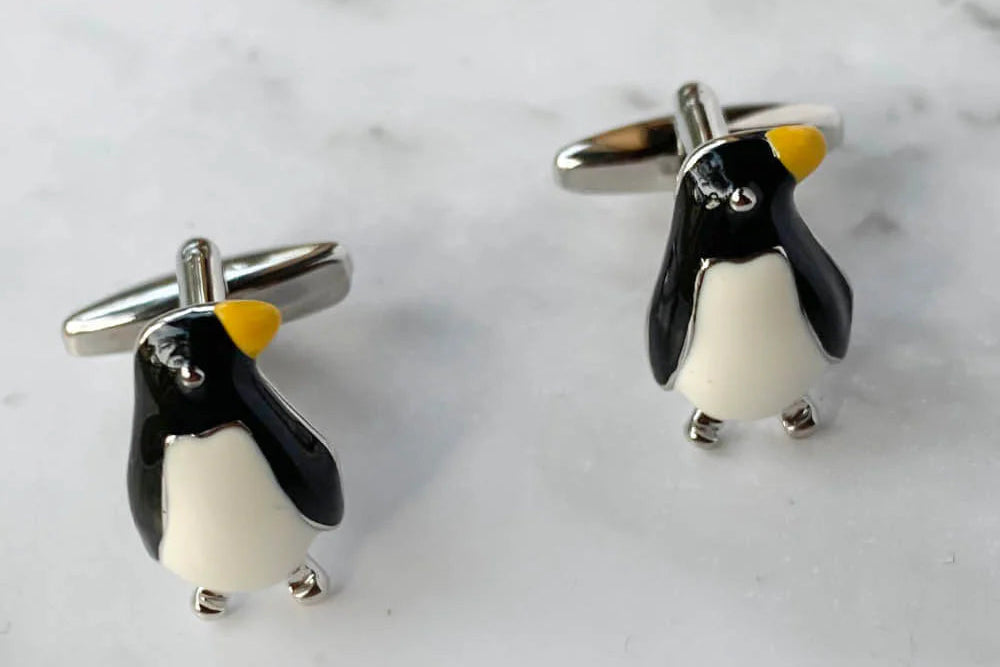 Penguin-shaped cufflinks on a marble surface