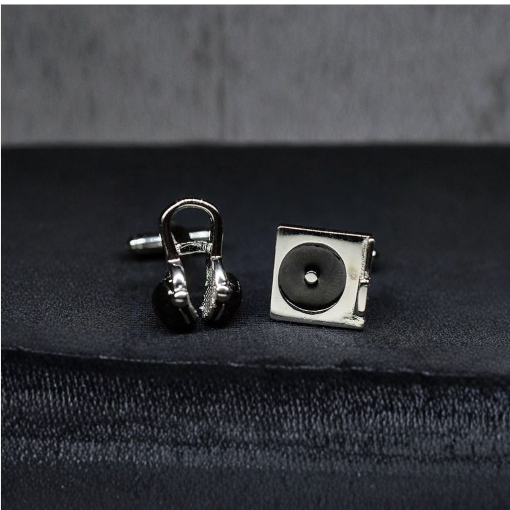 DJ Silver cufflinks shaped like a record player and headphones on a dark fabric background