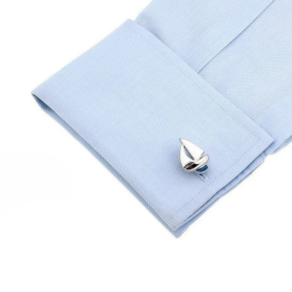 Silver boat-shaped cufflink on a light blue shirt cuff