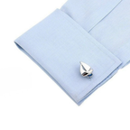 Silver boat-shaped cufflink on a light blue shirt cuff