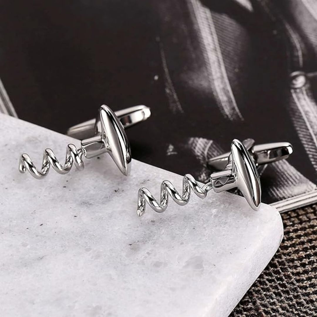 Silver corkscrew cufflinks on a marble surface with a blurred background