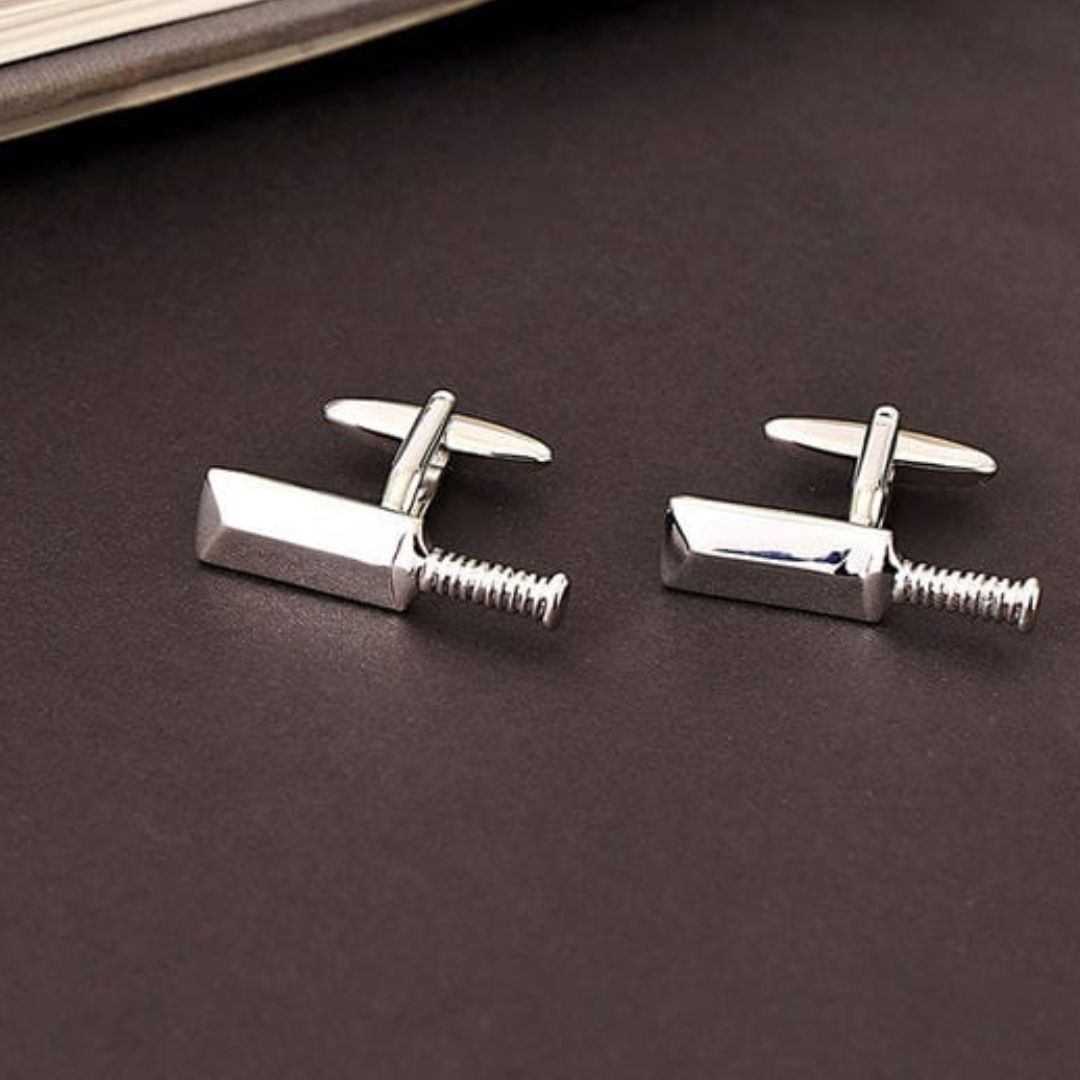 Silver cricket bat cufflinks on a dark surface