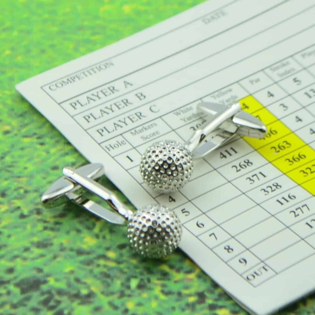 Silver golf ball cufflinks on a golf scorecard with a green background