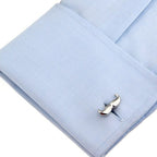 Silver mustache-shaped cufflink on a light blue dress shirt.