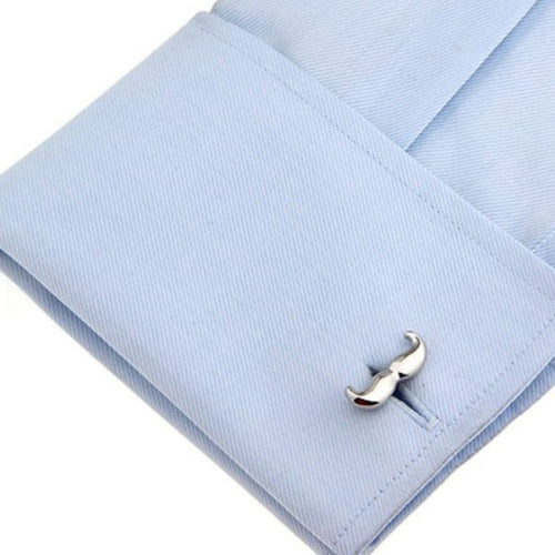 Silver mustache-shaped cufflink on a light blue dress shirt.
